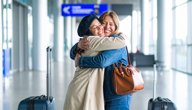 women embracing in emotional reunion hug at airport